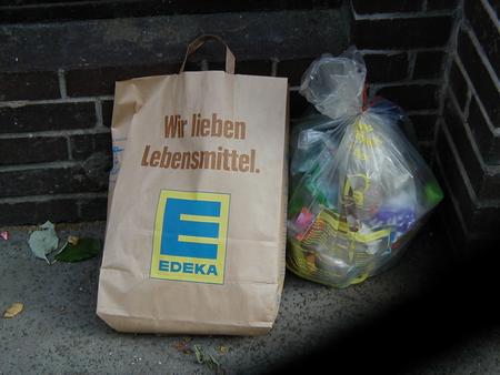 Foto mit einer Papier-Einkaufstüte am Müll, Aufdruck auf der Tüte ist Wir lieben Lebensmittel.